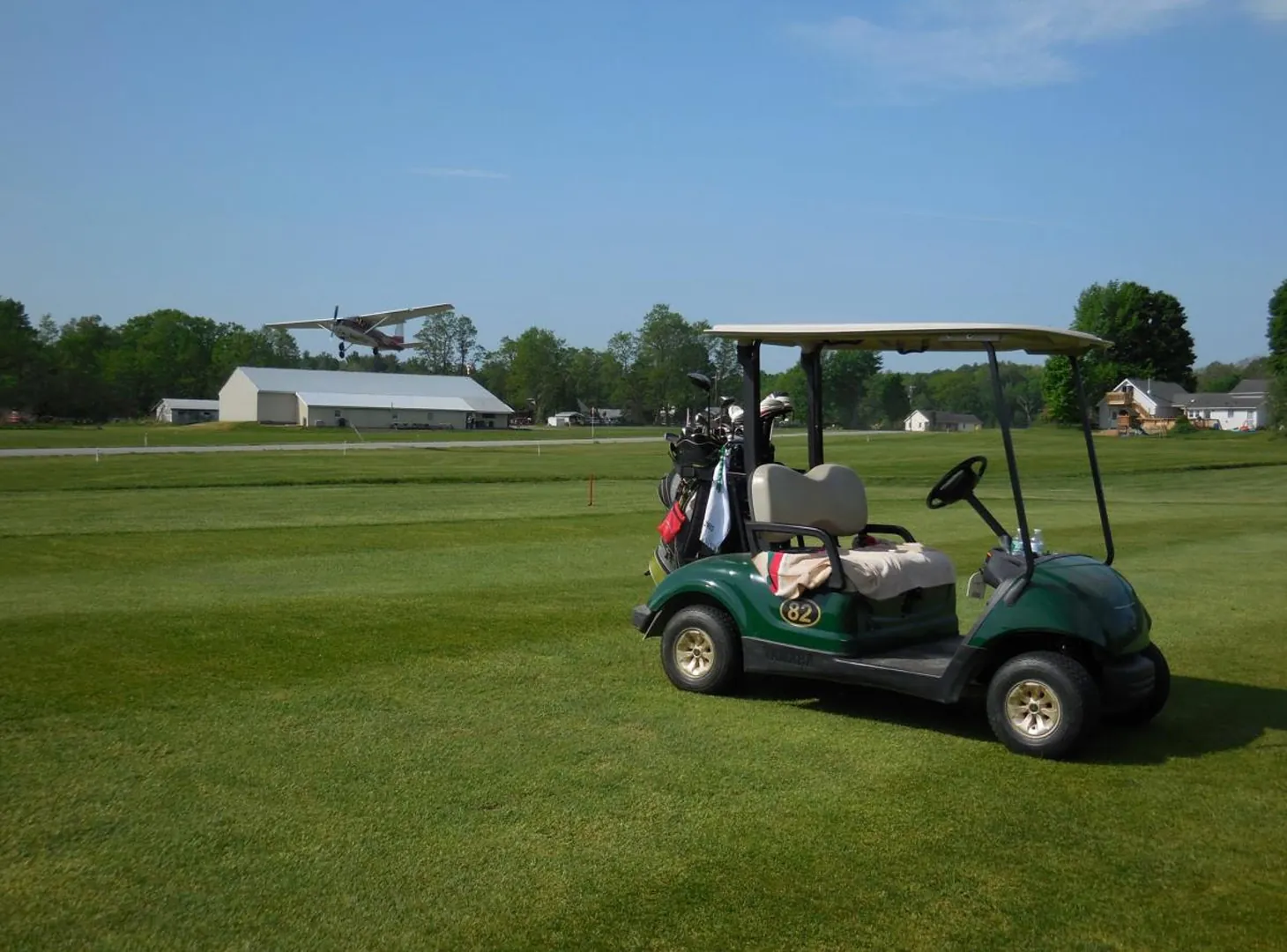 Golf cart on the fairway as a plane lands behind it